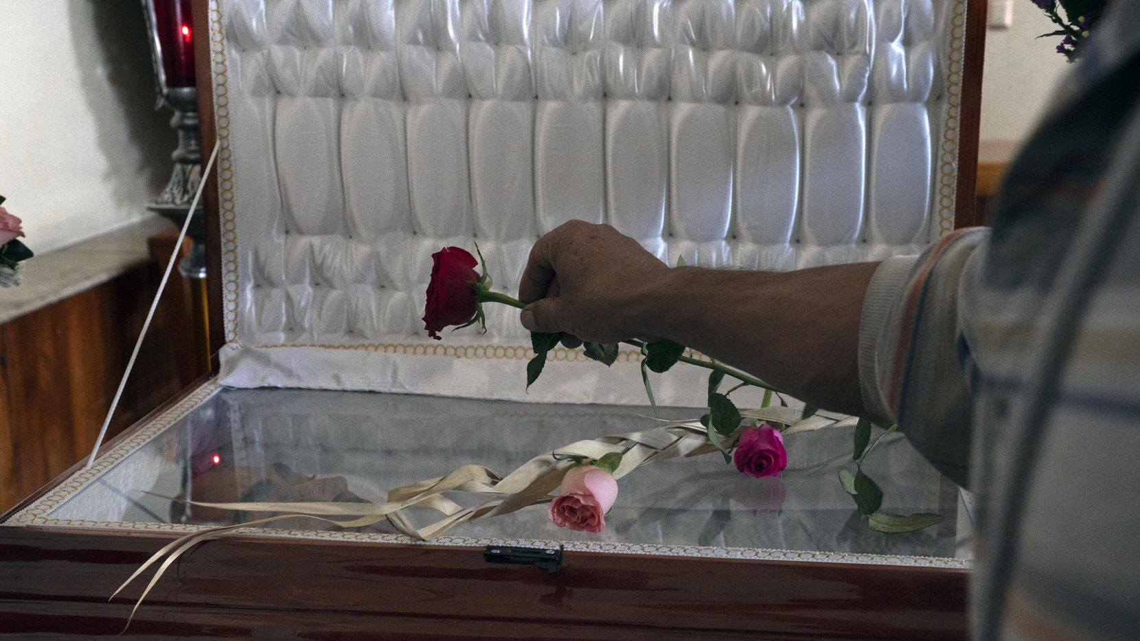 Un amigo coloca una rosa en el ataúd que contiene los restos del periodista asesinado Armando Linares en Zitácuaro, en el estado de Michoacán, México, el miércoles 16 de marzo de 2022.(Marco Ugarte / ASSOCIATED PRESS)