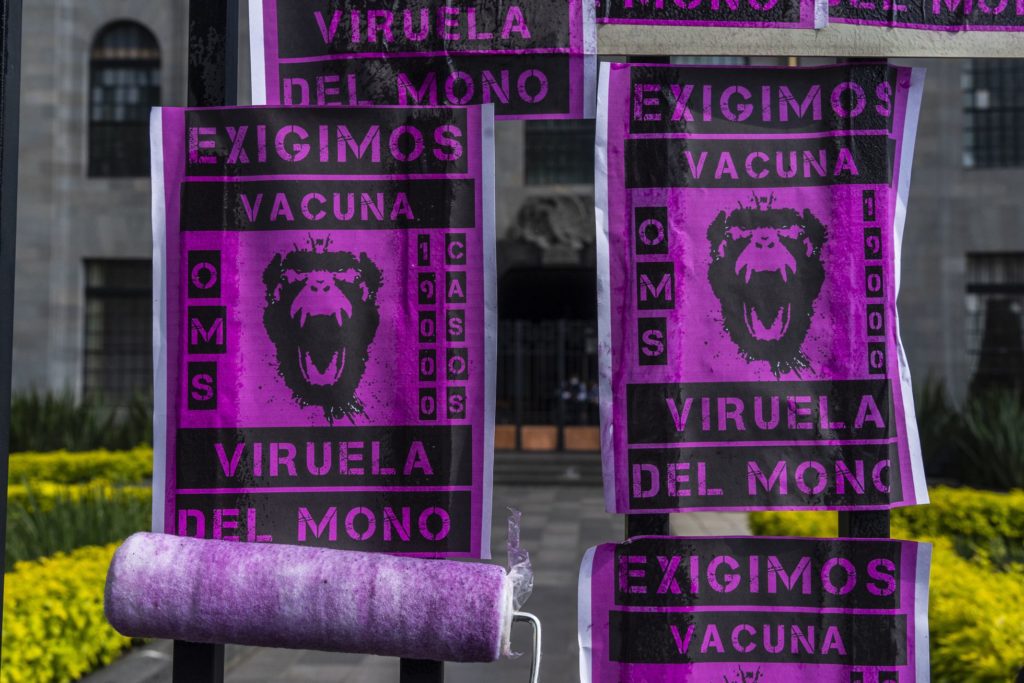 Durante la protesta de este martes, activistas pegan panfletos exigiendo vacunas contra la viruela mono. IÑAKI MALVIDO