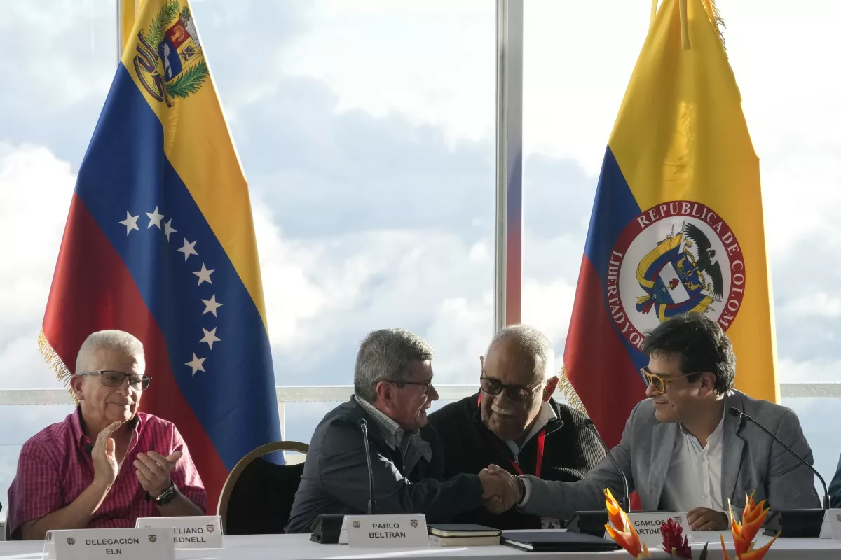 Pablo Beltrán, representante de la guerrilla colombiana Ejército de Liberación Nacional (ELN), segundo por la izquierda, estrecha la mano con Iván Danilo Rueda, alto comisionado para la paz de parte del Gobierno colombiano, en la reanudación de los diálogos de paz después de una suspensión de tres años, en el hotel Humboldt en Caracas, Venezuela, el lunes 21 de noviembre de 2022. El hombre sentado entre ambos no fue identificado. A la izquierda, el representante del ELN Aureliano Carbonell. (Ariana Cubillos / Associated Press)